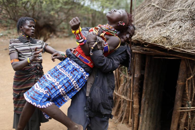 A man holds a girl as she tries to escape when she realised she is to to be married, about 80 km (50 miles) from the town of Marigat in Baringo County
