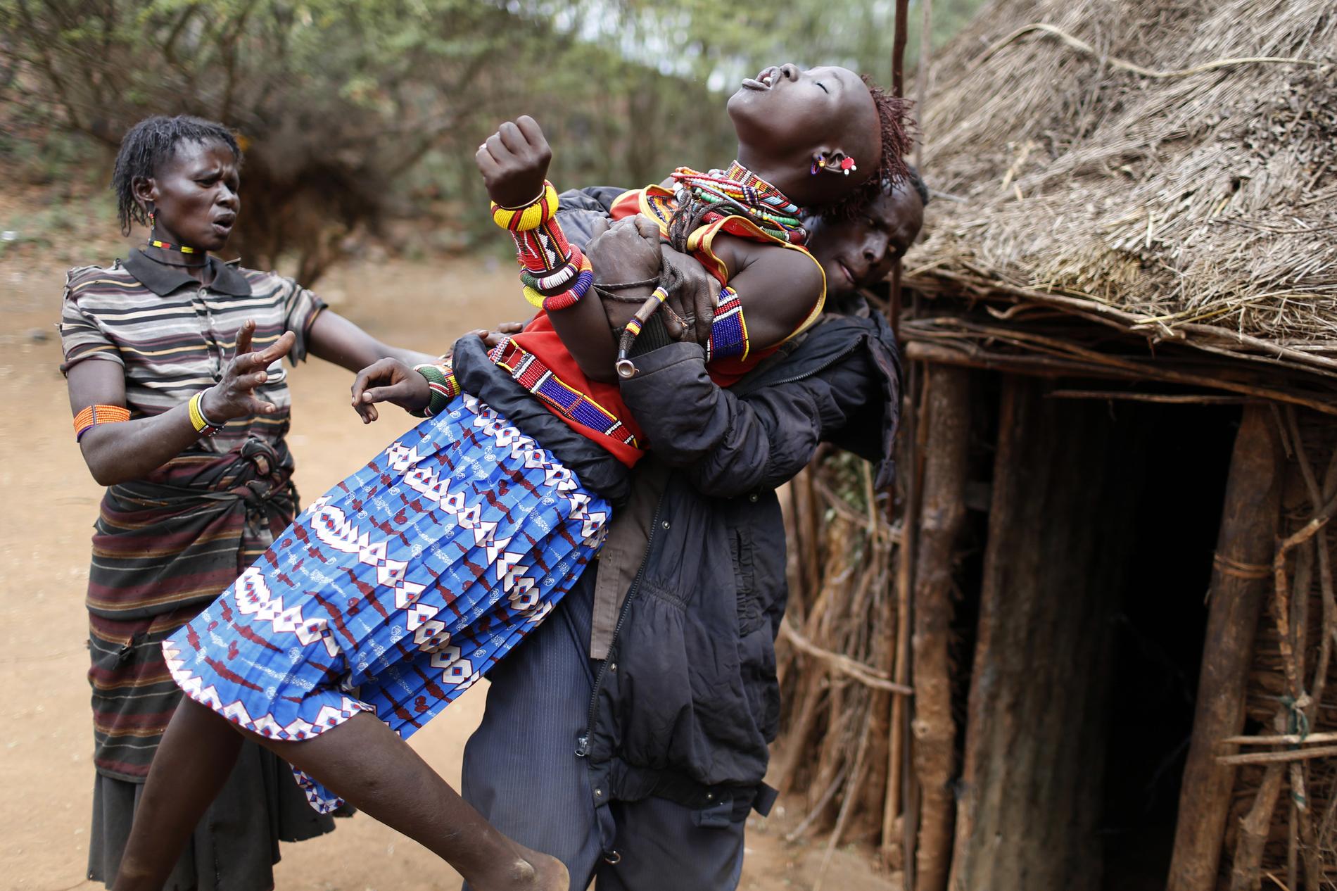 A man holds a girl as she tries to escape when she realised she is to to be married, about 80 km (50 miles) from the town of Marigat in Baringo County